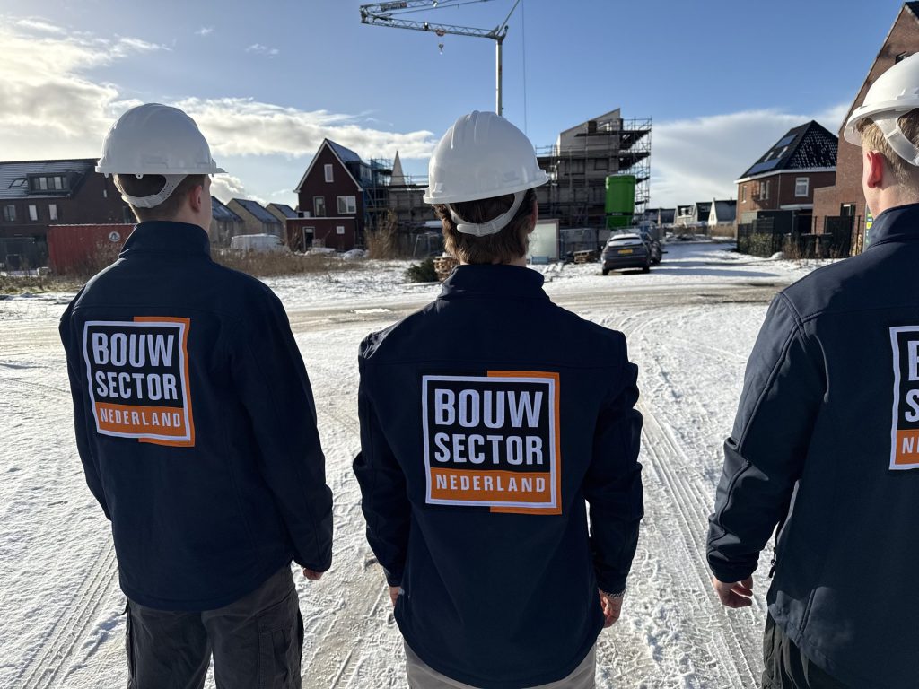 Drie vakmensen van Bouwsector Nederland met witte helm op een nieuwbouwlocatie in de sneeuw